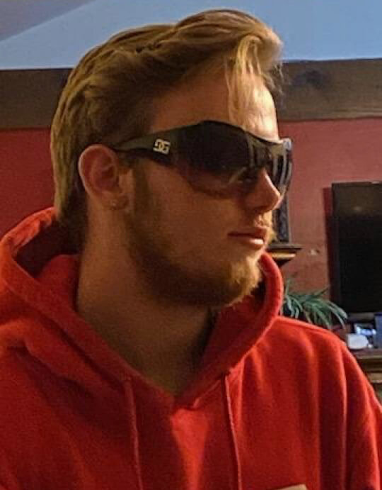 A photo of Patrick Michael Ramsey wearing sunglasses and a red hoodie